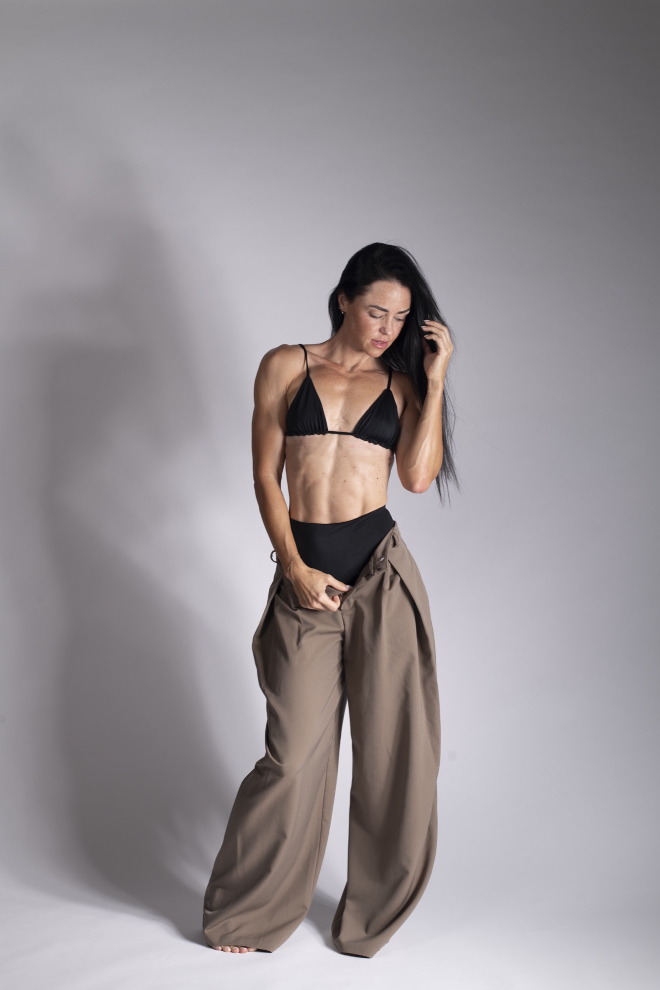 Courtney in a black top and tailored trousers